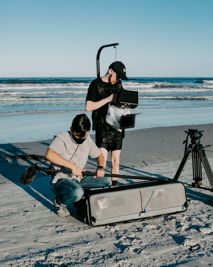 a man is filming another man on the beach